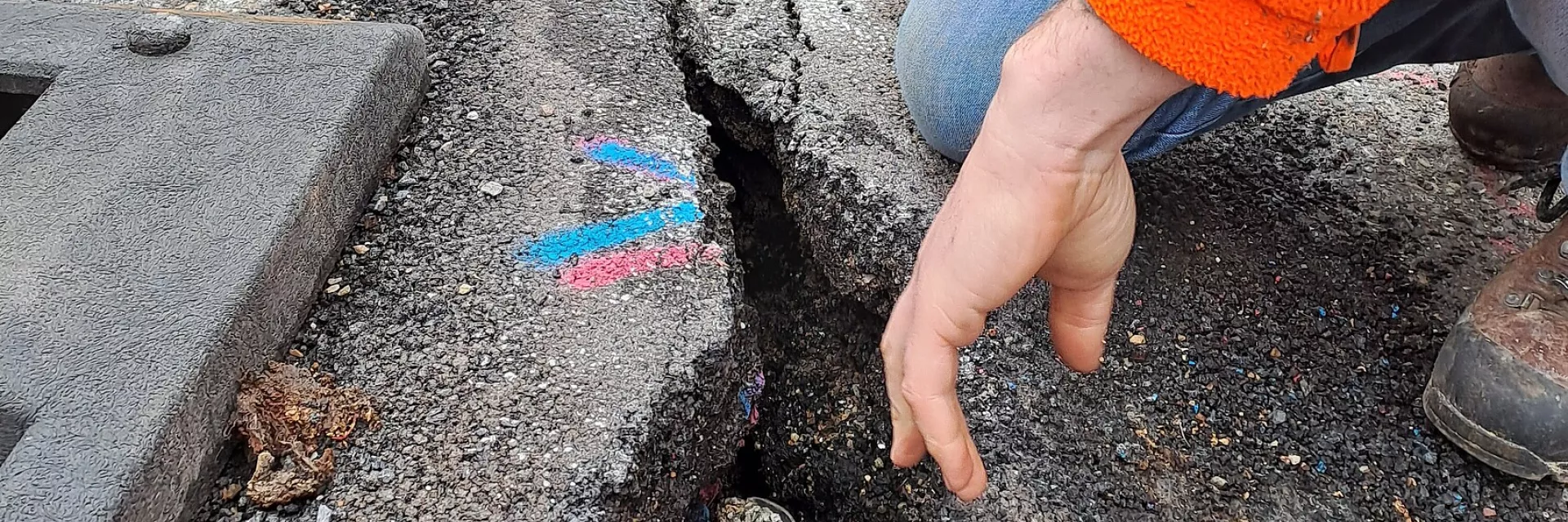 Ausschnitt aus einer Fahrbahndecke mit Längsspalt in Dreiecksform und farbigen Markierungen